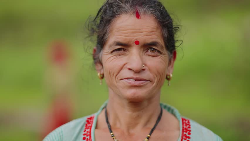 Close-up of Indian female farmer from village smiling warmly into the camera, traditional attire and natural light, 4k video