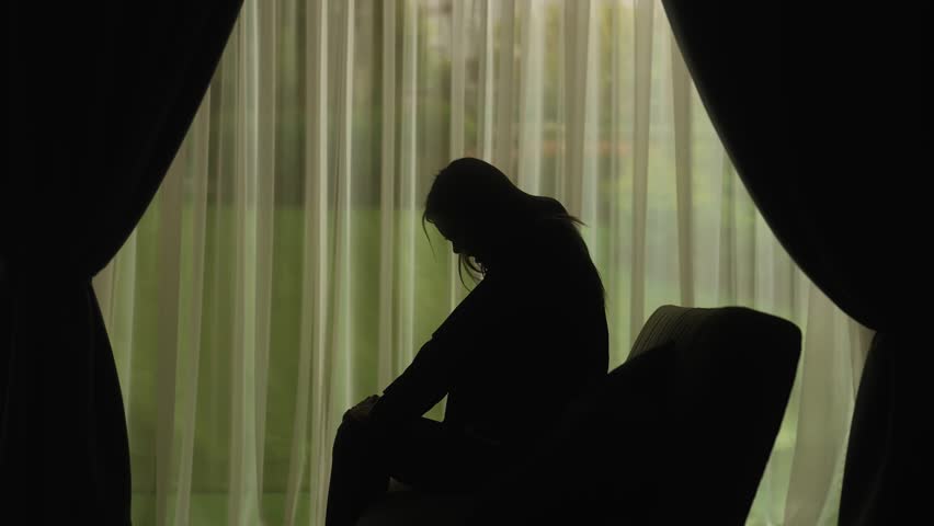 A silhouette of a woman screaming and expressing anger or frustration in front of sheer curtains, conveying emotion and intensity. Mental Health Concept. Slow motion.