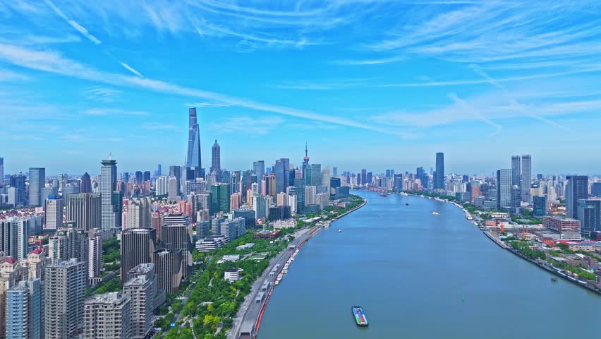 Shanghai, China - July 2nd 2025: 4K real time Aerial view of Shanghai skyline and winding river on sunny day, with blue sky background.