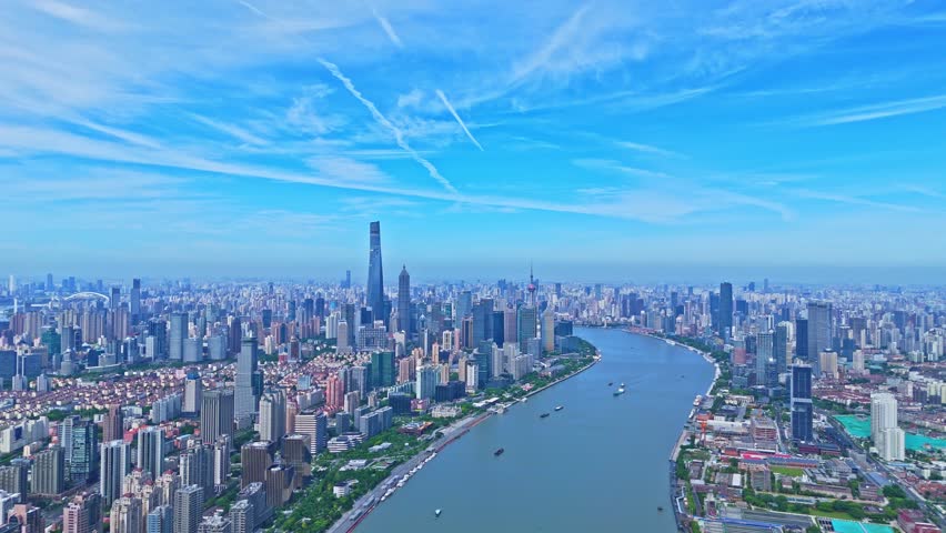 Shanghai, China - July 2nd 2025: 4K real time Aerial view of Shanghai skyline and winding river on sunny day, with blue sky background.