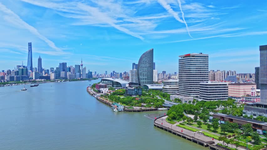 Shanghai, China - July 2nd 2025: 4K real time Aerial view of Shanghai skyline and winding river on sunny day, with blue sky background.