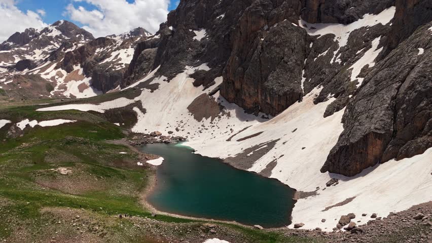 A mountain range with a large body of water in the middle. The water is blue and surrounded by snow