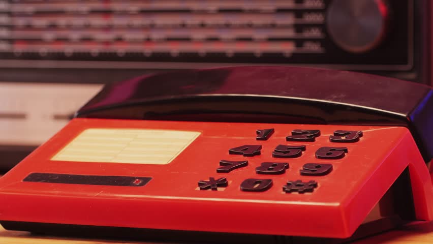 Red retro vintage phone telephone ringing off on table, close up macro 90s mobile retro smartphone.