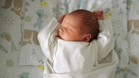 Newborn baby sleeps soundly swaddled in white wrap lying on blanket. Peaceful expression and relaxed posture convey sense of deep comfort - Powered by Shutterstock - Get 15% off with code: PIKWIZARD15