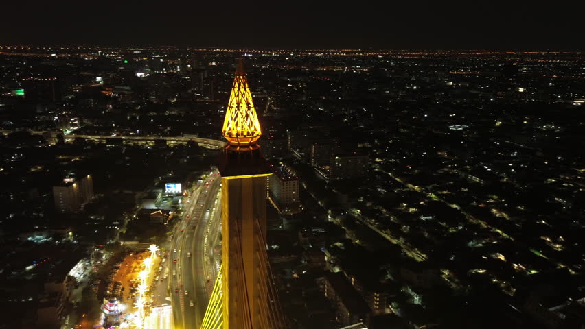 Aerial around view of illuminated Rama VIII Bridge at night. Cable-stayed bridge crossing Chao Phraya River in Bangkok, Thailand, 4k