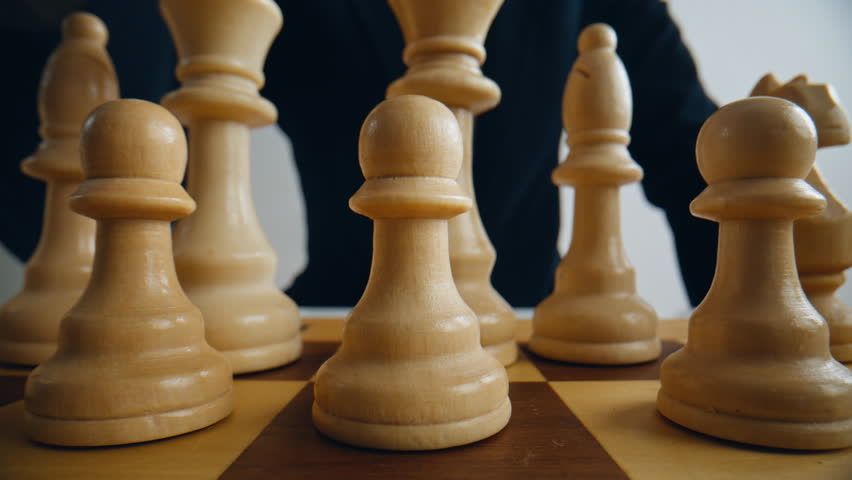 Gamer fingers shifting chess on competition grid closeup. Logic match challenge board. Anonymous male hand controlling figures on playfield indoors. Corporate thinker applying clever tactics strategy