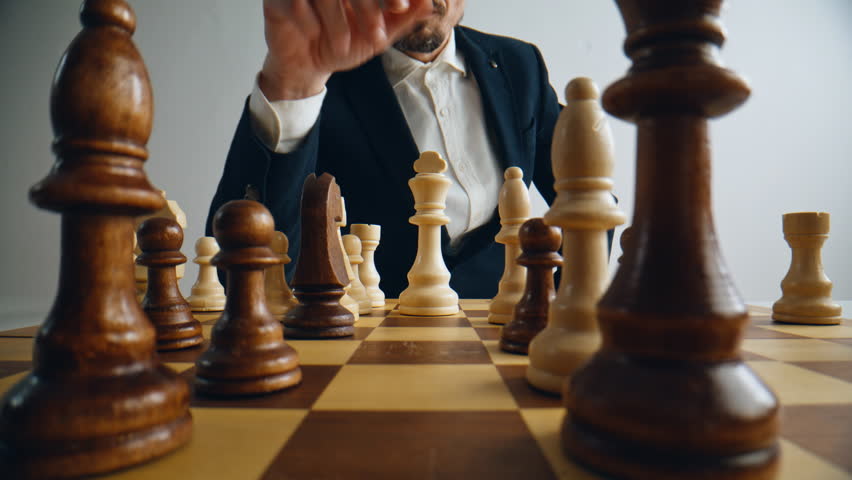 Unknown man playing chess logic board game closeup. Player hand moving figure on chessboard in strategy way closeup. Unrecognizable businessman enjoying smart tactic alone. Business strategy concept