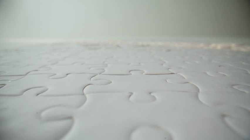 Detailed view of finished white puzzle set on blank table. Bright mind jigsaw with connected pieces on surface closeup zoom on shot. Problem-solving task planning and completed project idea concept