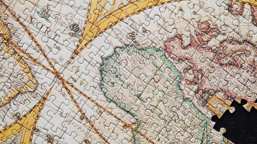 Unfinished global puzzle resting on black surface displaying partial formation closeup. Antique styled map missing section illustrating challenge completion. Unresolved objective metaphor concept