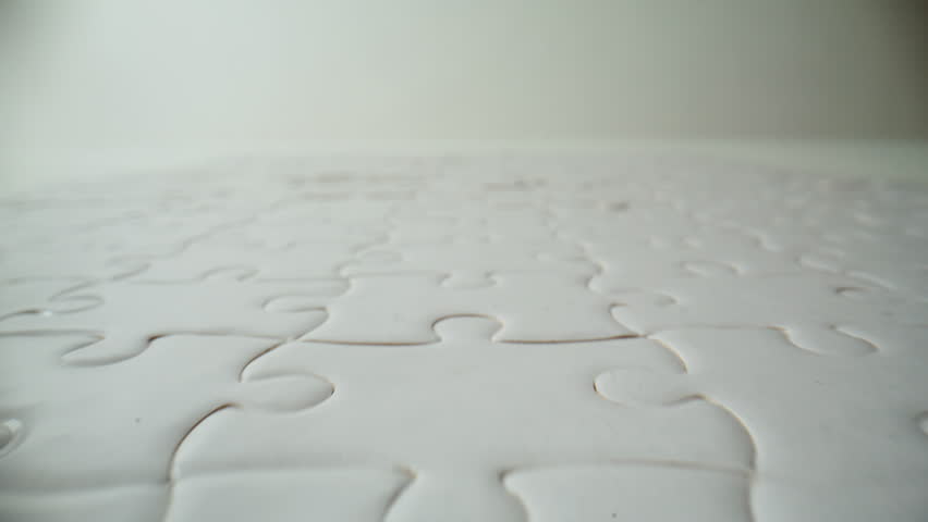 Closeup white completed puzzle placed on empty table. Light brain jigsaw teaser with bonded segments on surface zoom on moving shot. Challenge resolution organization and finished assignments concept