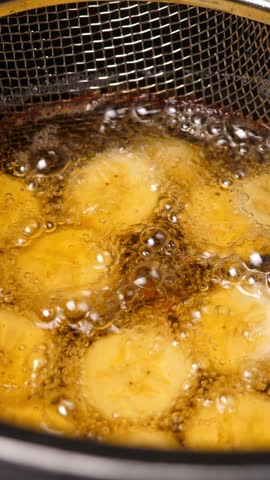 Cooking fried bananas in fryer fat. Closeup. Vertical footage