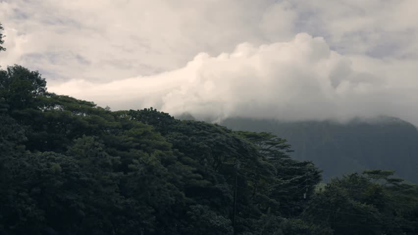 traffic in Hawaii with mountains and clouds in background 