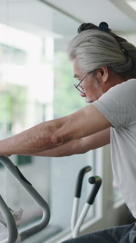 Senior Man Pedaling Exercise Bike Maintaining Fitness And Well-Being During Retirement