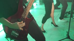 Artists perform at rock music festival at night. Close-up of members of rock band playing heavy rock on stage. Bassist plays a red guitar and the legs of a female vocalist wearing high heels on stage. - Powered by Shutterstock - Get 15% off with code: PIKWIZARD15