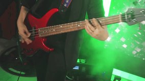Close-up of bass player's hands while playing guitar at live music concert. Female bass player plays bass guitar during rock concert. Guitarist plays chords, strums strings to rhythm of music piece. - Powered by Shutterstock - Get 15% off with code: PIKWIZARD15