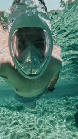 A Man Swims Over a Reef in Transparent, Shallow Water - Vertical Shot
