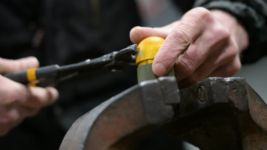 Slow-motion: A technician in a Ukraine drone workshop uses a vise and pliers to remove a grenade