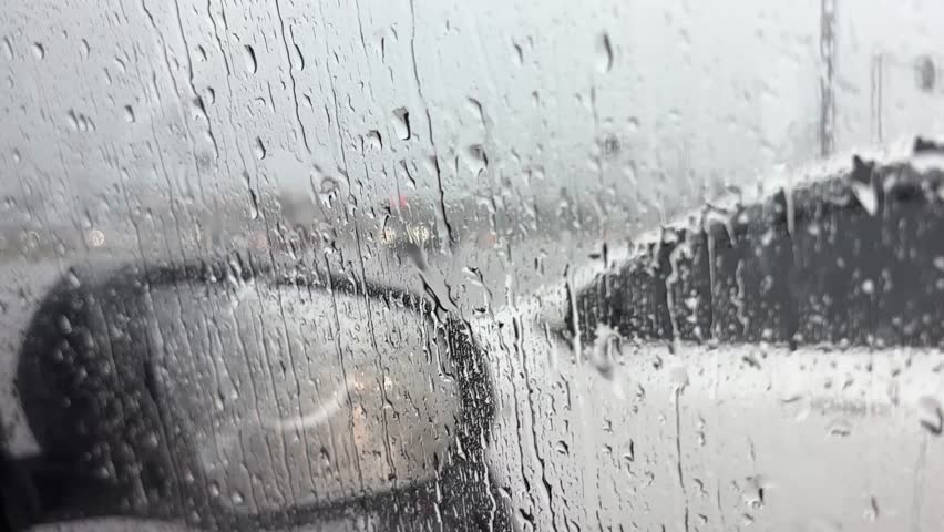 Traffic in rainy day with road view through car window with rain drops