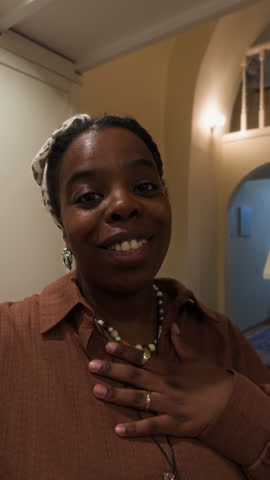 Vertical UGC of young black mom vlogging on camera while helping daughter cooking lunch at modern home kitchen