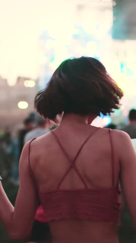 vertical shot. girl at a concert of her favorite music group, dancing and smiling from happiness, celebration and excitement. Young woman dancing at a concert, having fun on an open area. 
