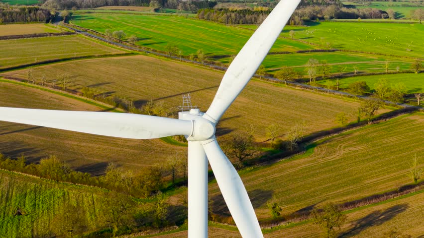 Windmill wind farm with rotating large windmill turbines generating renewable energy. Wind turbine operating giant blades to support green electricity production. Operating wind blades generating low