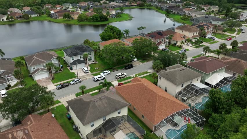 Rich families living in upper class housing area of Orlando. Private pond in yard of villa. Transparent roof of private swimming pool. Aerial establishing wide shot. Florida, USA.