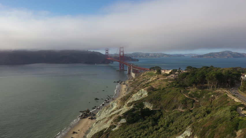 Golden Gate Bridge Partially Covered In Fog Under Moody Sky In San Francisco, California. wide drone shot