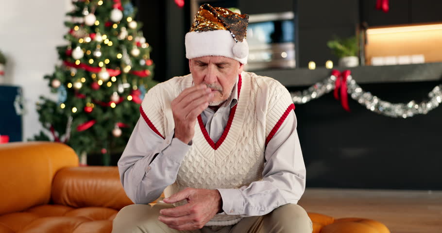 Christmas, sad and lonely senior man in home lounge for regret, memory or cancelled plans. Old person, living room and upset on festive holiday, sofa and xmas with depression or stress in house