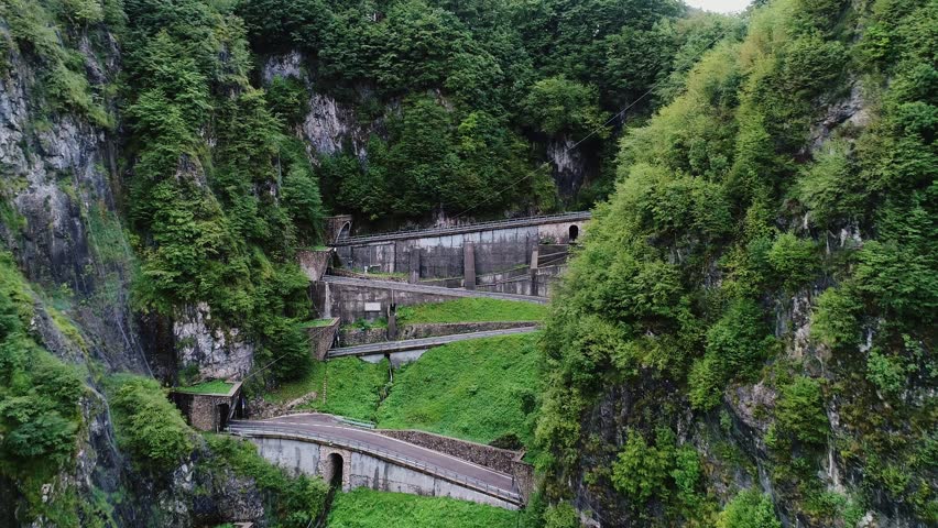 Curving alpine road cuts through steep cliffs of San Boldo Pass under cloudy sky