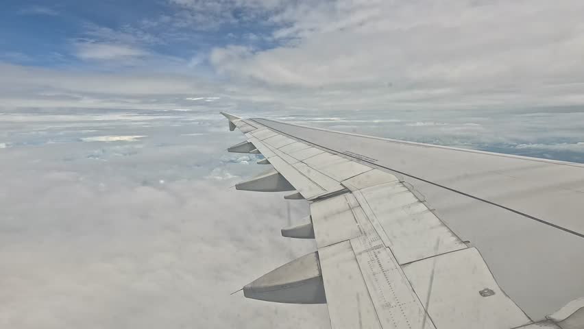 Footage of aerial landscape with blue sky clouds. Taken from airplane window.