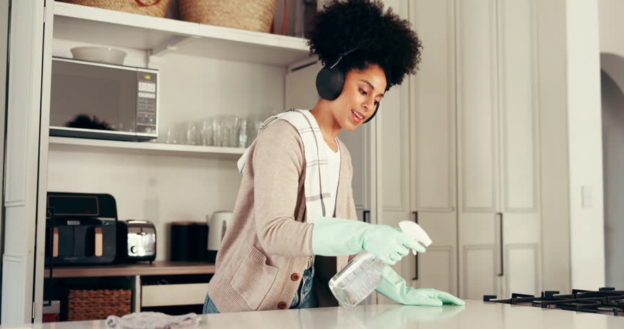 Cleaning, woman and dancing with headphones, kitchen and chores with chemical in home and streaming. Happy, person and glove for protection in house, music and listen to playlist on radio or hygiene