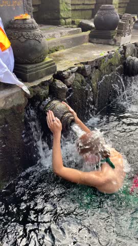 Close-up of woman performing traditional water purification ritual at the temple in Ubud Bali, Indonesia. Spiritual moment ideal for religion, culture, and travel content.
