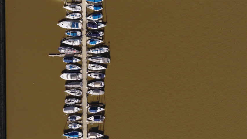 Top-down drone shot of a row of white yachts docked on Matanza River in Puerto Madero, Buenos Aires, Argentina.
