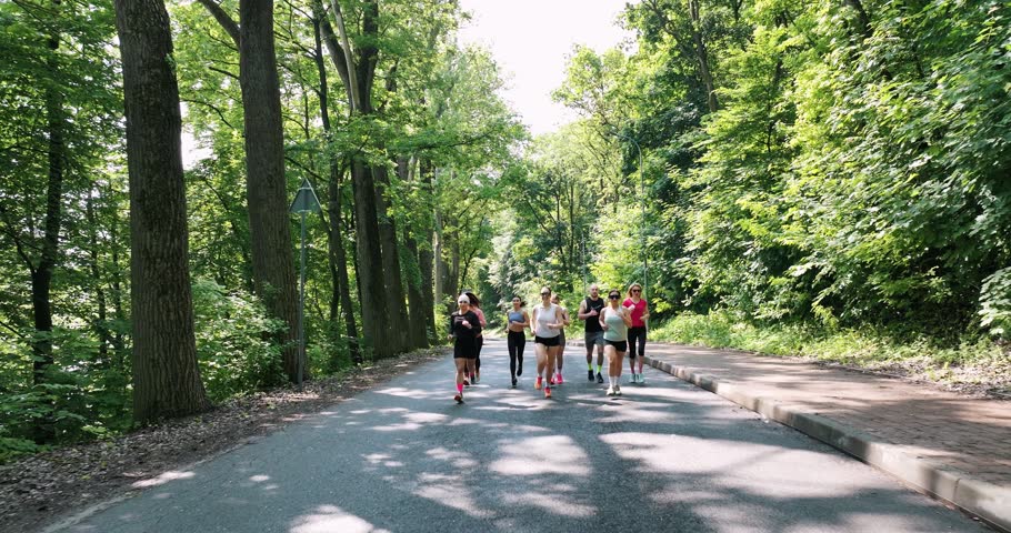 Adults are running together. Group of people are outdoors.
