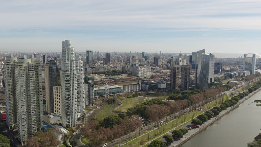 High-altitude drone glides over Buenos Aires, Argentina, capturing the modern skyline of Puerto Madero, including Alvear Tower, YPF Tower, and the distinctive bridge area near Río de la Plata.