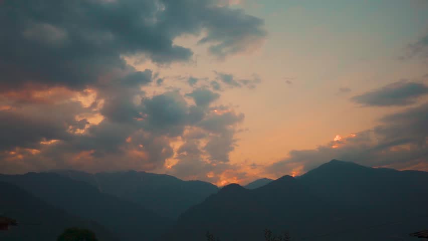 Landscape shot of sunset with clouds above the Himalayan mountains during the monsoon season as seen from Naggar near Manali in Himachal Pradesh, India. Clouds above the Himalayas in sunset.