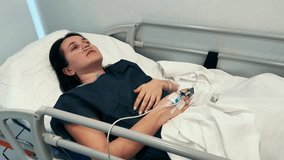 Patient lies in bed in the hospital with intravenous drip in the hand after surgery. Healthcare and medical treatment concept. High quality 4k footage - Powered by Shutterstock - Get 15% off with code: PIKWIZARD15