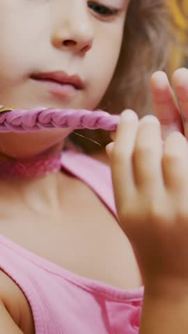 Beautiful blond girl, of seven years old, braided two pigtails, do a hairstyle with pink locks of hair in a beauty salon, a hairdresser