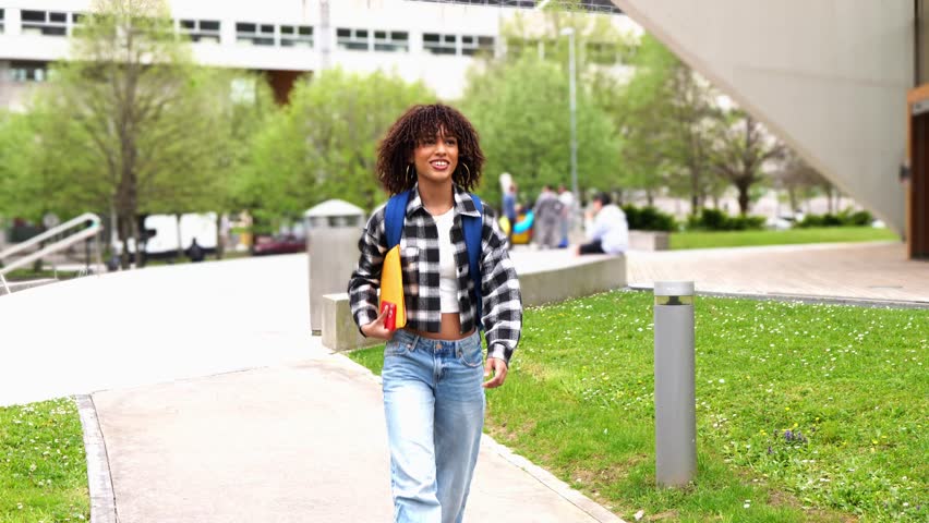 Young african american woman navigating college campus with cheerful stride, embodying academic aspirations and youthful energy