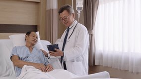 Experienced Asian senior doctor visiting talking to elderly male patient resting in hospital bed, providing care and support in hospital room. - Powered by Shutterstock - Get 15% off with code: PIKWIZARD15