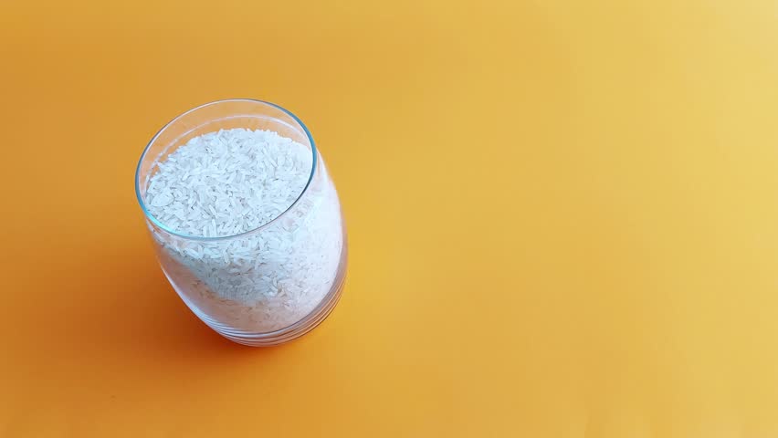 Gentle hands seal a white rice jar beneath soft kitchen light. The smooth lid clicks into place with quiet care. A tactile, calm moment of warmth and home ritual