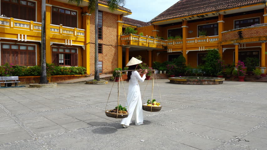 Asian woman wearing vietnam culture traditional and sell the fruit on the street, Hoi an in Vietnam.