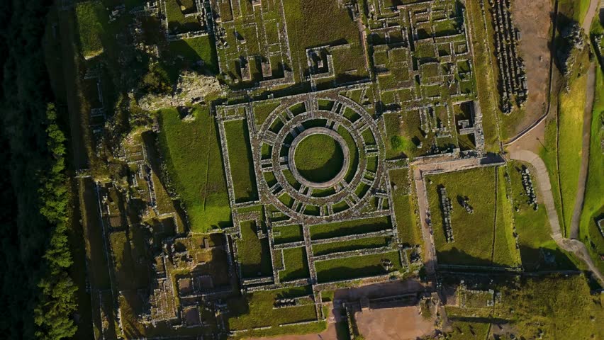 A mesmerizing top-down drone shot spins while descending, creating a hypnotic vortex effect over the circular stone foundations of an ancient Inca tower at the Saqsaywaman ruins.