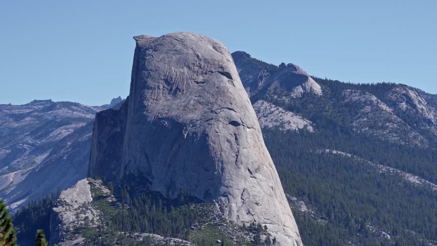 Footage featuring a slow zoom-in on the iconic Half Dome granite formation in Yosemite National Park, California