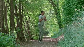 A man diligently practices various martial arts techniques while walking along a peaceful wooded path. A man engages in training while immersed in a serene and beautiful nature trail - Powered by Shutterstock - Get 15% off with code: PIKWIZARD15