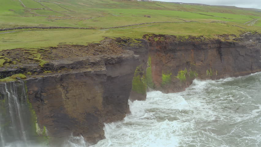 Aerial tracking shot captures the wild Atlantic Ocean beating the Cliffs of Moher in Doolin during a storm
