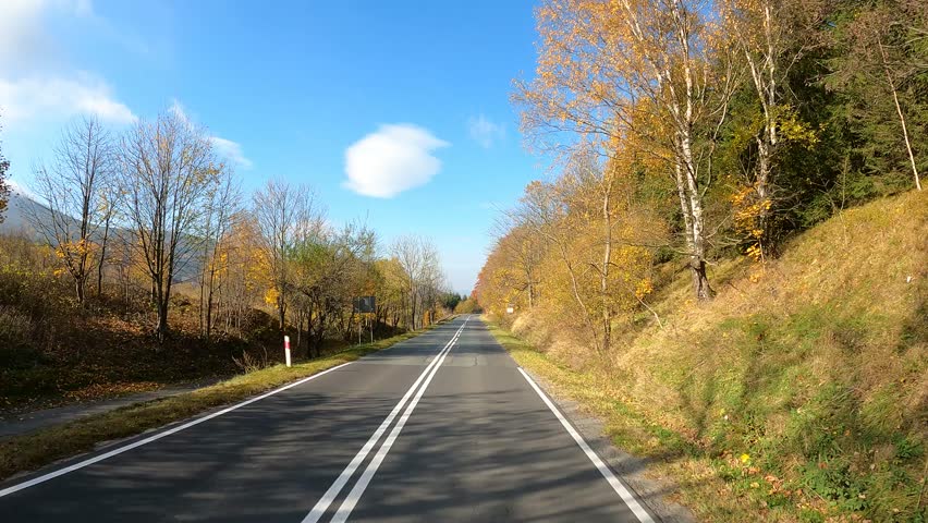 car driving on autumn road in countryside in sunny weather
