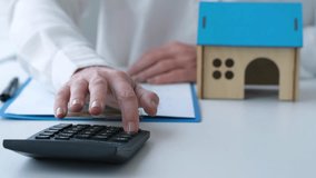 Female calculating mortgage cost on calculator and then writing. Expenses on refinancing of home loan. Real estate investment concept - Powered by Shutterstock - Get 15% off with code: PIKWIZARD15