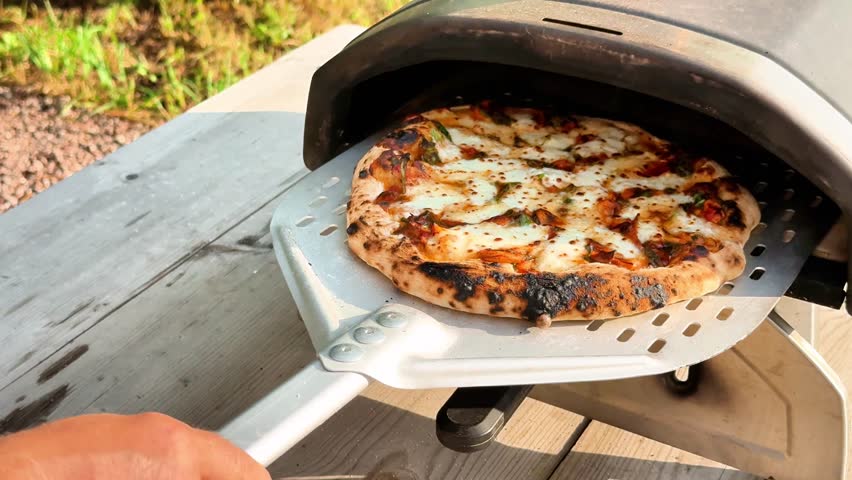 Homemade Pizza. Delicious fresh tomato mozzarella pizza out of home portable pellets oven. Outdoor pizza party.