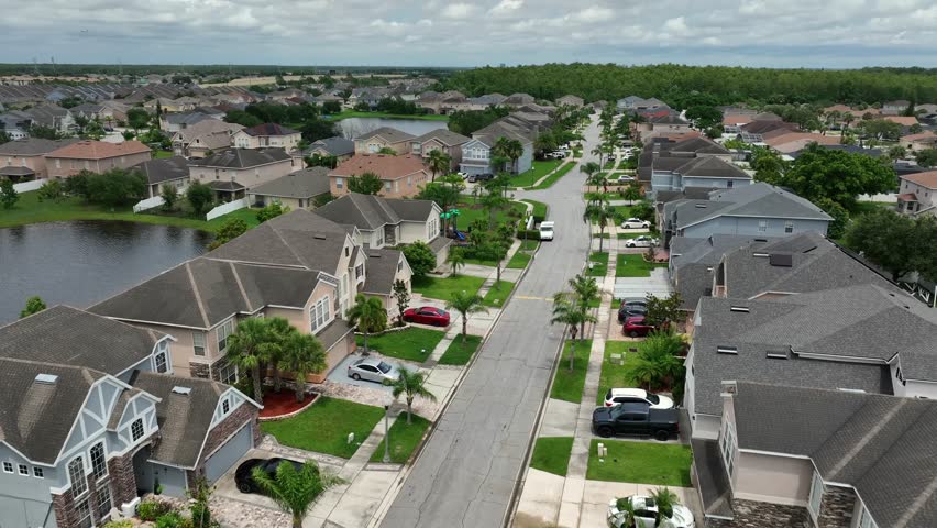 Aerial establishing shot of luxury neighborhood in suburb of Orlando, Florida. Exclusive houses with private lake view in America. Rising shot. Quiet and tropical homes.